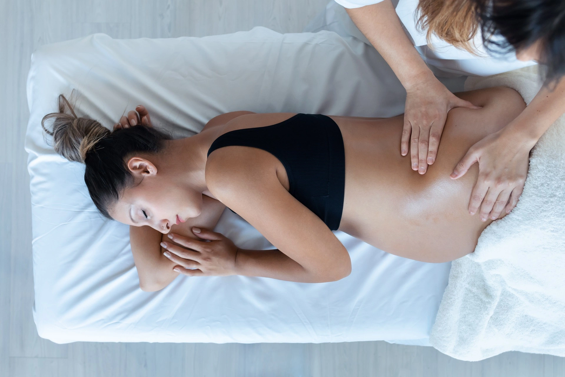 a woman lying on a bed with hands on her back