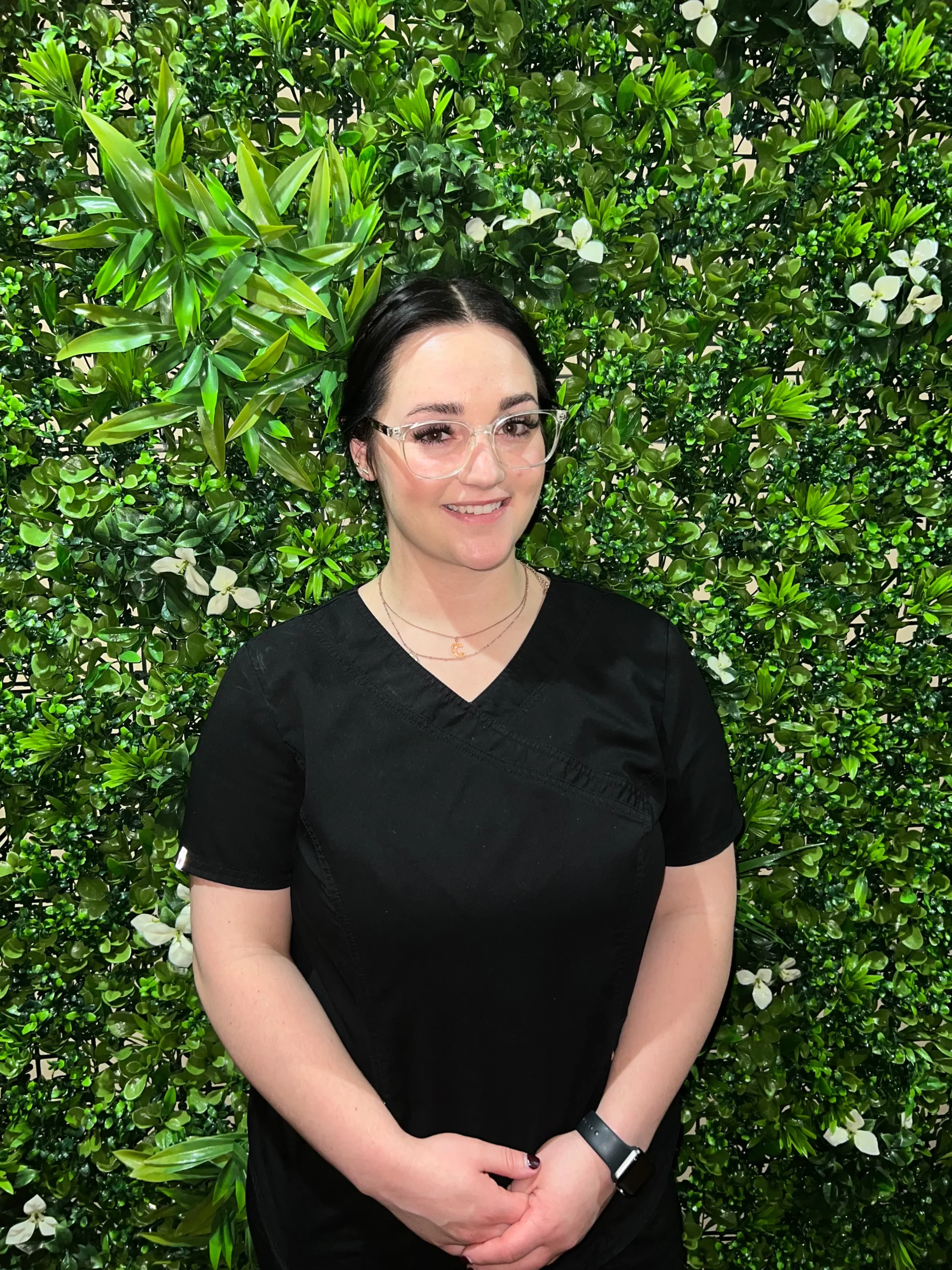 a woman in black shirt and glasses standing in front of a green wall