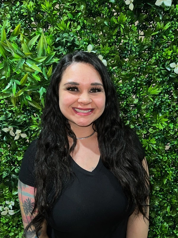 a woman smiling in front of a bush