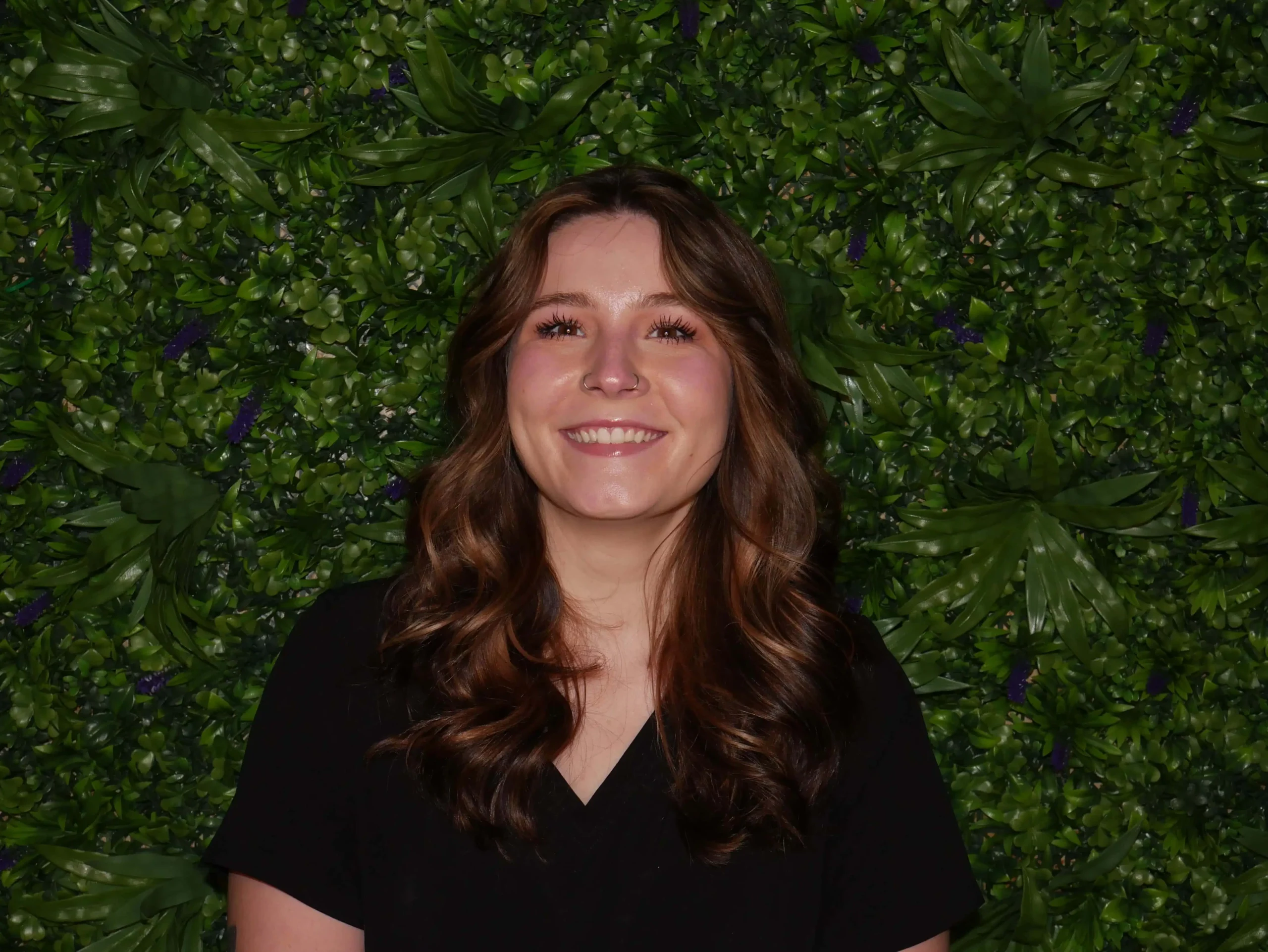 a woman smiling in front of a green wall