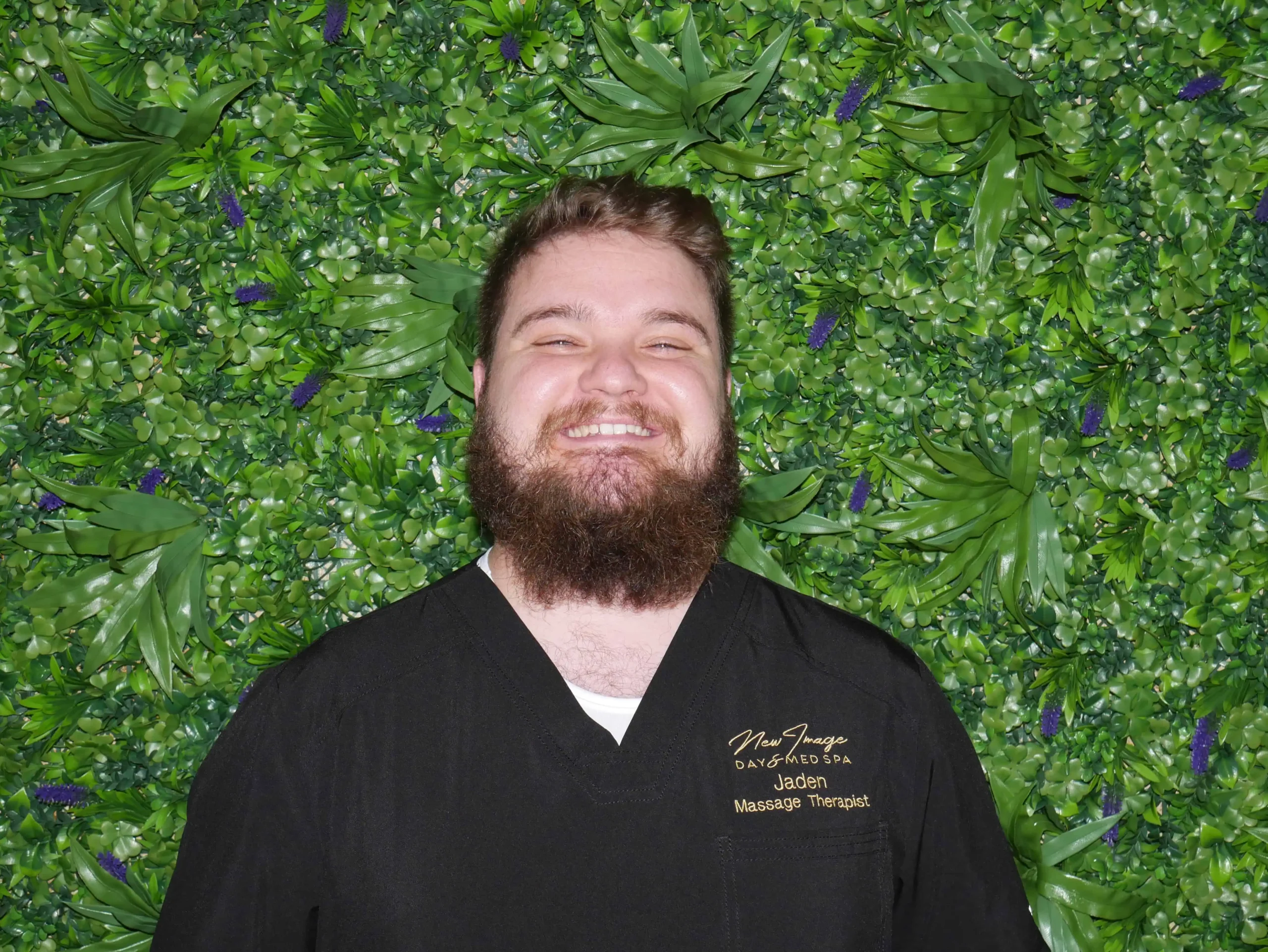a man smiling in front of a green wall