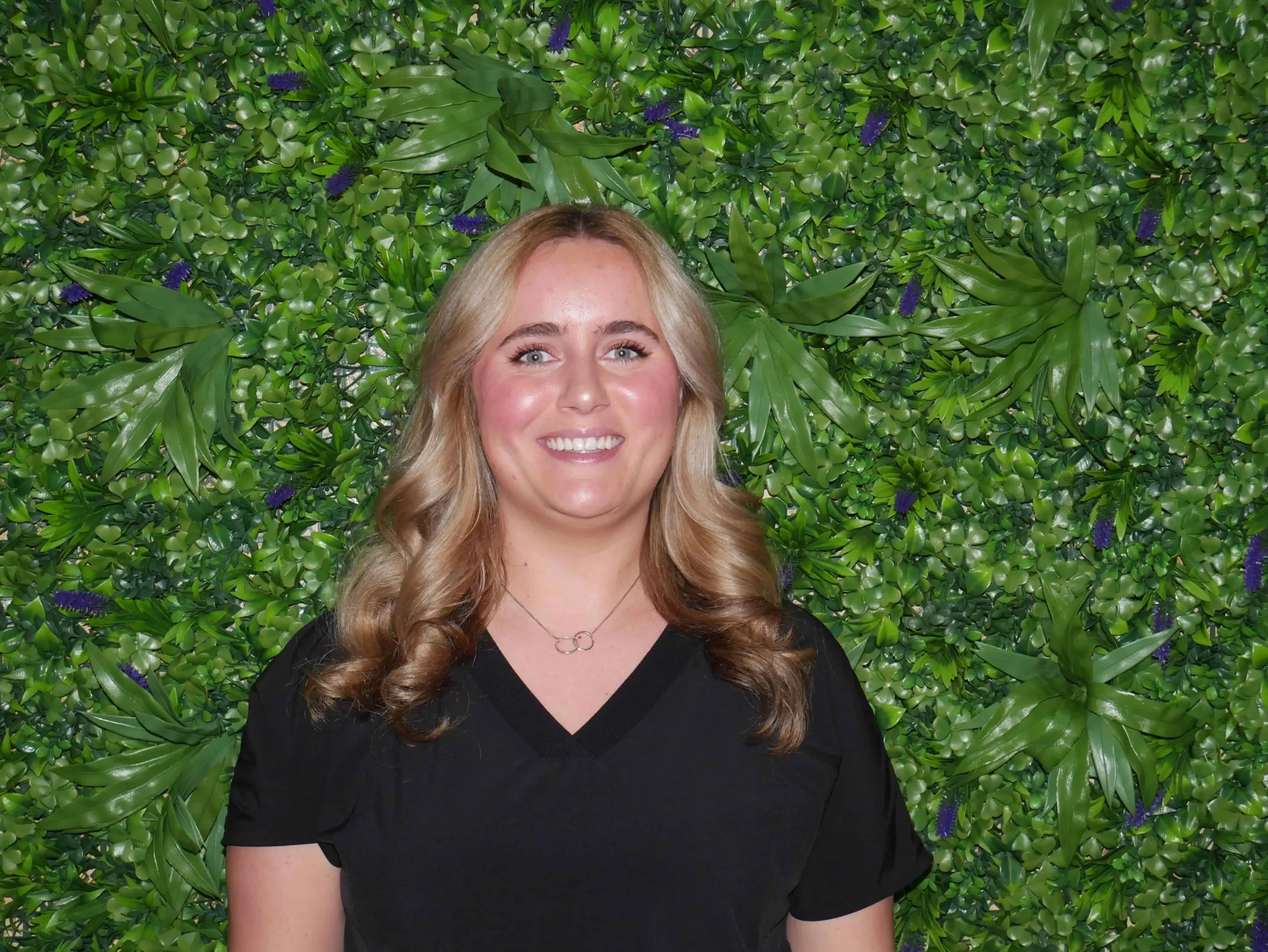 a woman smiling in front of a green wall