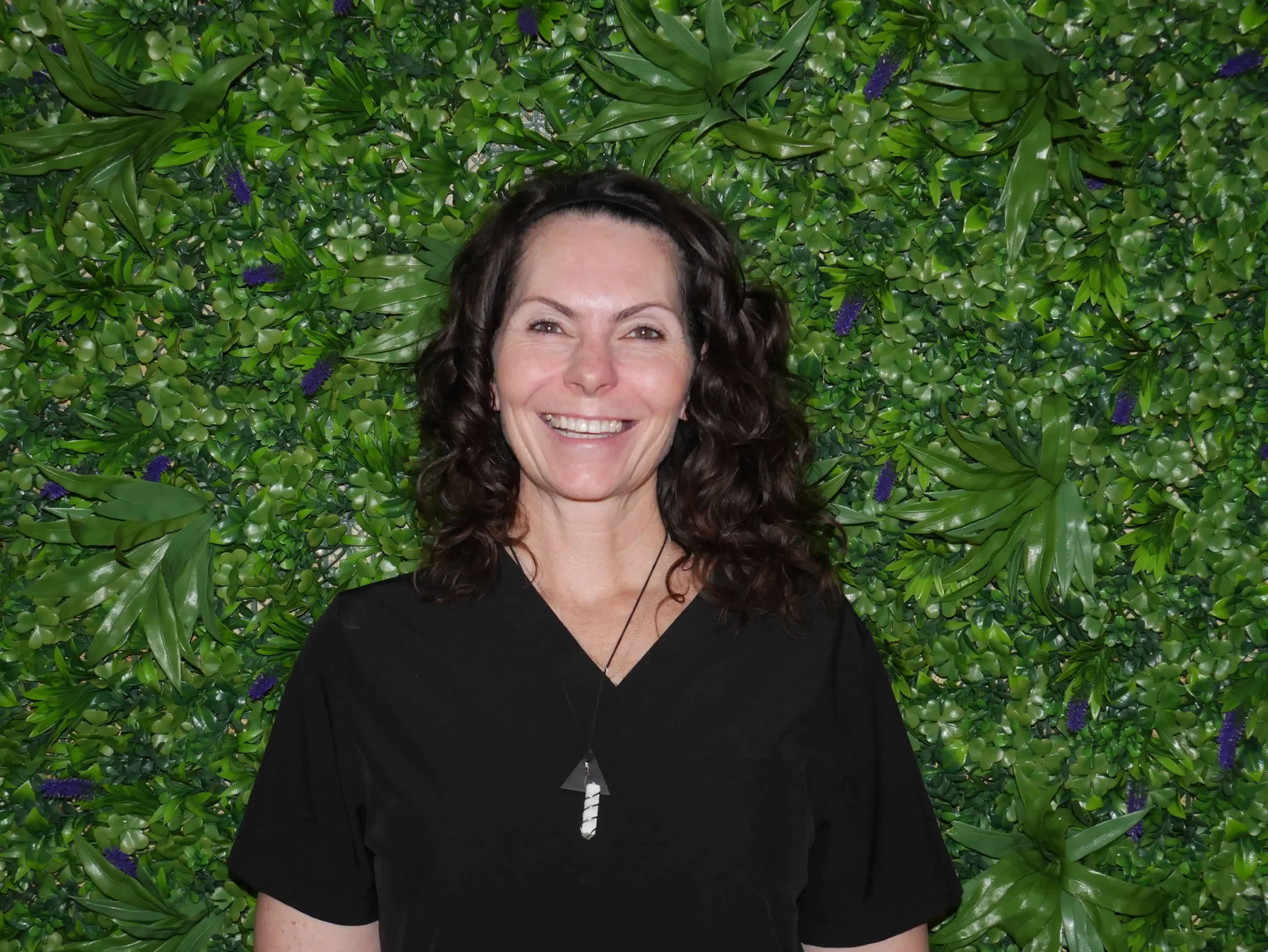 a woman smiling in front of a green wall